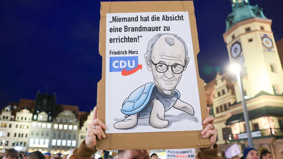 Ein Demo-Teilnehmer hält ein Plakat mit der Aufschrift «Niemand hat die Absicht eine Brandmauer zu errichten» hoch. Ein Demo-Teilnehmer hält ein Plakat mit der Aufschrift «Niemand hat die Absicht eine Brandmauer zu errichten» hoch.