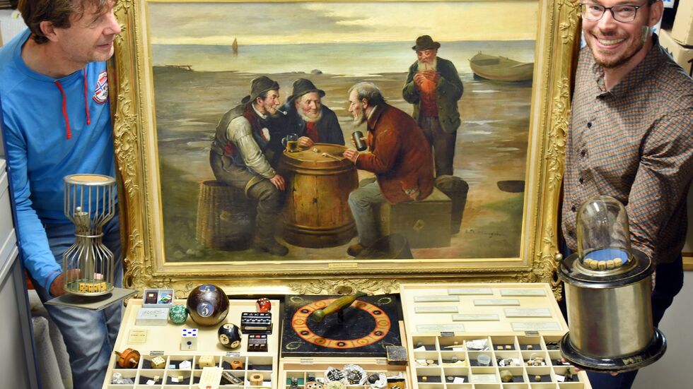 Der Würfelspielesammler Jakob Gloger (r) steht mit seinem Vater Andre Gloger in seiner Würfelspielesammlung, zu der neben vielen Tausenden Würfel auch ein großes Gemälde gehört, das Fischer beim Würfeln auf einem Heringsfass um 1910 zeigt. Der Würfelspielesammler Jakob Gloger (r) steht mit seinem Vater Andre Gloger in seiner Würfelspielesammlung, zu der neben vielen Tausenden Würfel auch ein großes Gemälde gehört, das Fischer beim Würfeln auf einem Heringsfass um 1910 zeigt.