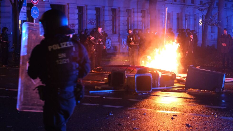 Polizisten stehen auf der Eisenbahnstraße in Leipzig vor brennenden Gegenständen.