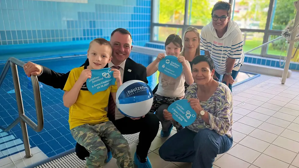 Stellvertretend für elf Förderschulen im Landkreis Bautzen nahm die Lindenschule Bautzen am 20. August 2026 die Badekappen entgegen. Auf dem Foto am Therapiebecken der Förderschule sind Schulleiterin Gundula Rabold (hinten rechts) mit zwei Schülern der Lindenschule sowie Landrat Udo Witschas, Kathrin Winkler (vorne rechts), Geschäftsführerin des Tourismusverbands Lausitzer Seenland e. V. und Therés Wurzler (Mitte), Projektkoordinatorin Netzwerk Barrierefrei im Lausitzer Seenland zu sehen. Mit der Spende erhalten die Badekappen der 5-Seen-Challenge einen nachhaltigen Nutzen für den Schwimmunterricht von Kindern und Jugendlichen mit Förderbedarf.