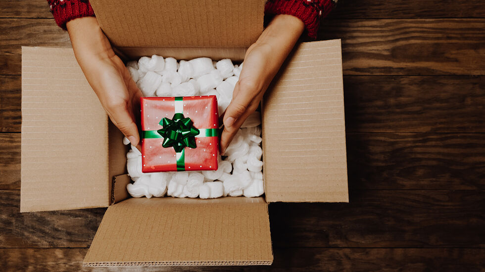 Eine Frau hält ein Paket mit einem Geschenk.