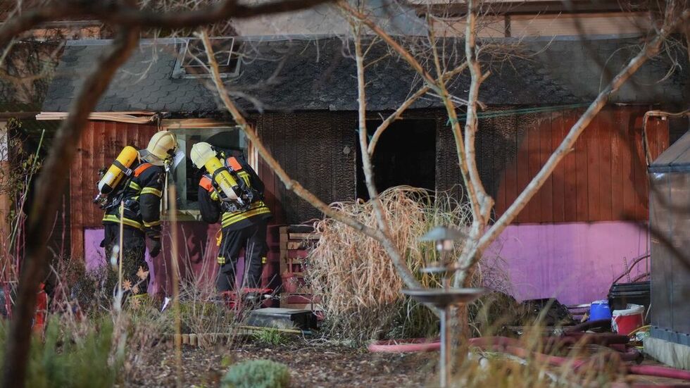 Die Feuerwehrleute untersuchen die Gartenlaube nach dem Feuer.