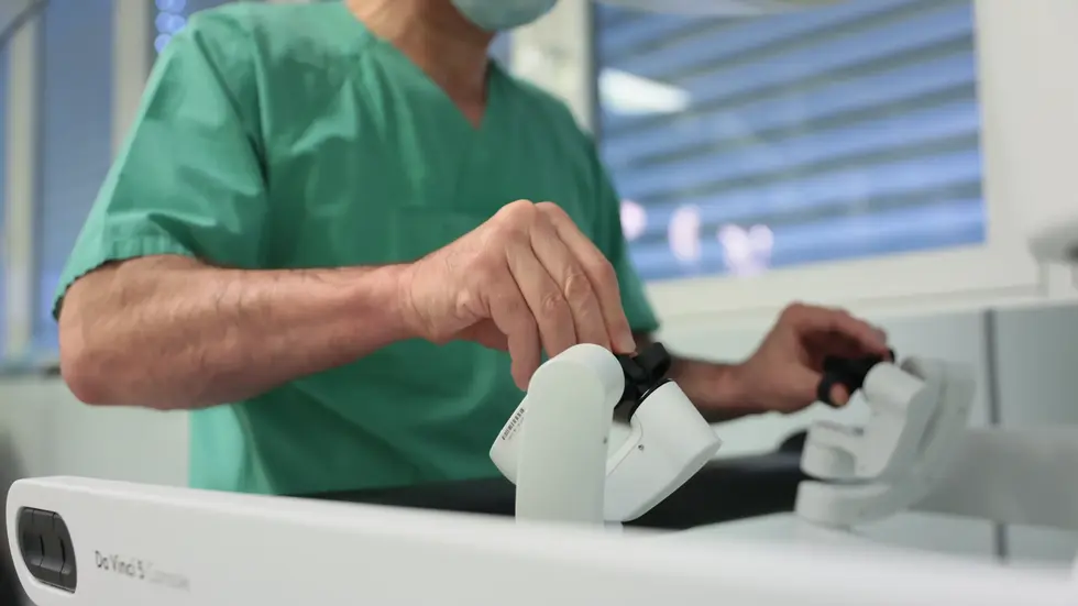 An der Konsole steuert der Operateur die Instrumente des da Vinci 5. Eine hochauflösende dreidimensionale Darstellung des Operationsgebietes unterstützt ihn dabei, anatomische Strukturen präzise zu erkennen. An der Konsole steuert der Operateur die Instrumente des da Vinci 5. Eine hochauflösende dreidimensionale Darstellung des Operationsgebietes unterstützt ihn dabei, anatomische Strukturen präzise zu erkennen.