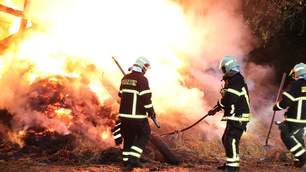 Das Heulager brennt lichterloh. Feuerwehrleute kämpfen gegen die Flammen an
