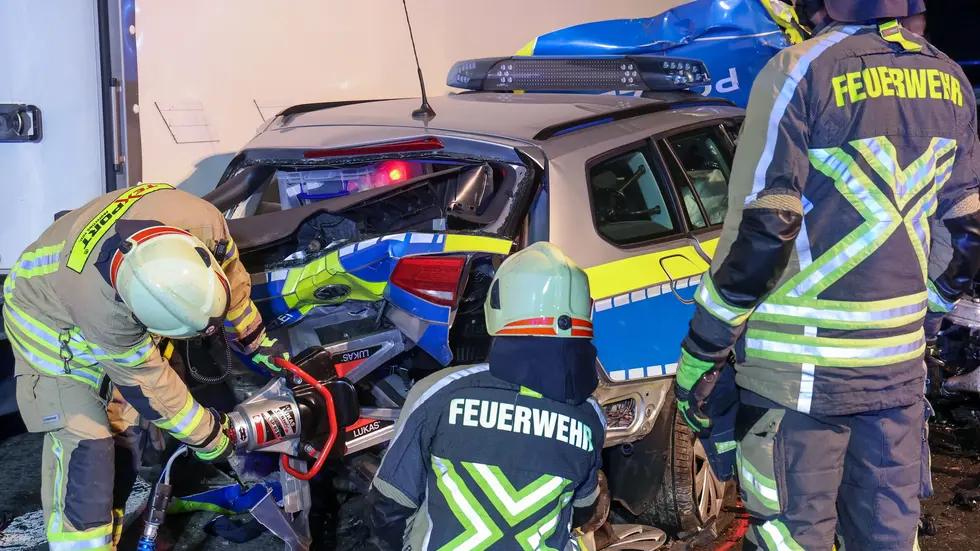 Ein Feuerwehrmann beim Aufflexen des Kofferraums des Polizeifahrzeugs. Darin befand sich eine Tasche mit einer Dienstwaffe. 