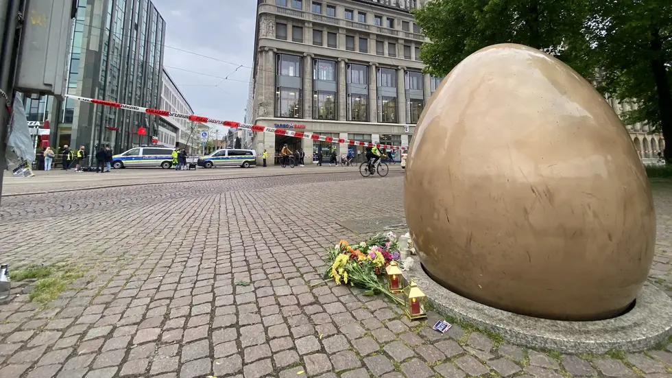 Am "goldenen Ei" gegenüber der Zufahrt haben Menschen Blumen abgelegt und Kerzen gestellt. Das Ei erinnert eigentlich die friedliche Revolution von 1989.