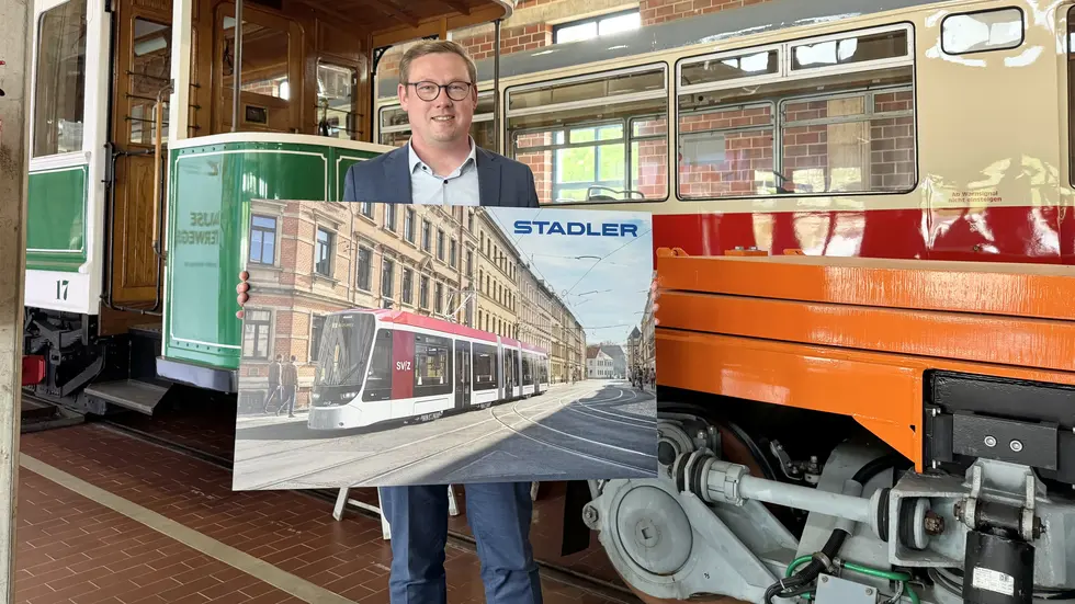 SVZ-Chef Sebastian Eßbach mit einem Schild, das eine neue Stadler-Bahn zeigt - eingefügt in die Zwickauer Bosestraße.