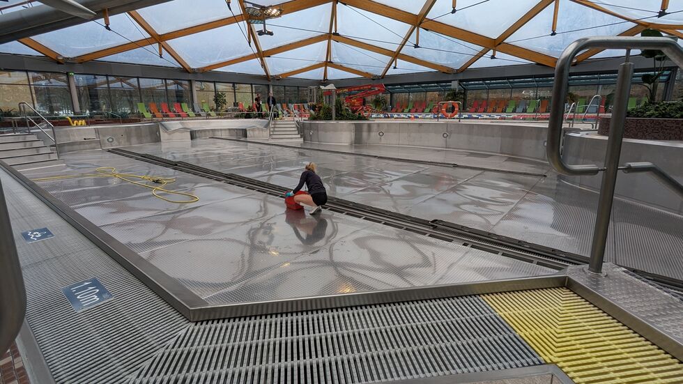 Eine Frau reinigt die Becken des Bades.