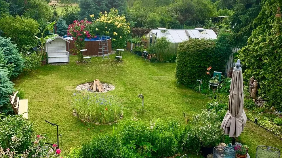 Blick aus der Vogelperspektive auf ein harmonisch angelegtes Gartenparadies mit blühenden Blumen, gepflegten Hecken, Bäumen und Sträuchern. Gewächshaus, gemütliche Sitzplätze, Feuerstelle und Planschpool laden zum Verweilen, Entspannen und Genießen ein. Blick aus der Vogelperspektive auf ein harmonisch angelegtes Gartenparadies mit blühenden Blumen, gepflegten Hecken, Bäumen und Sträuchern. Gewächshaus, gemütliche Sitzplätze, Feuerstelle und Planschpool laden zum Verweilen, Entspannen und Genießen ein.
