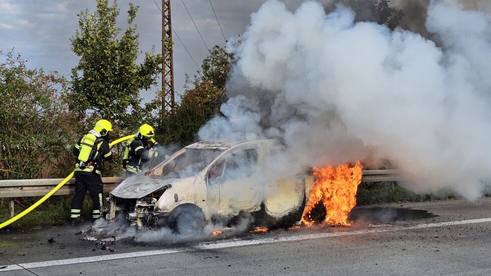 Die Flammen schlagen noch aus dem Heck des Citroen, während Feuerwehrleute den Brand bekämpfen.