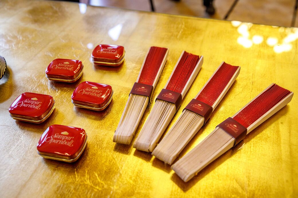 Die Besucher erhalten kirschrote Geschenke: Ein Fächer und Minzbonbons sorgen für Erfrischung warten auf die Gäste des Balls