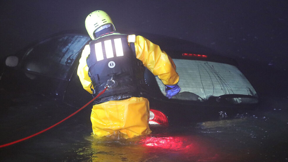 Ein Feuerwehrmann sichert den Peugeot vor dem Abtreiben in der Elbe 