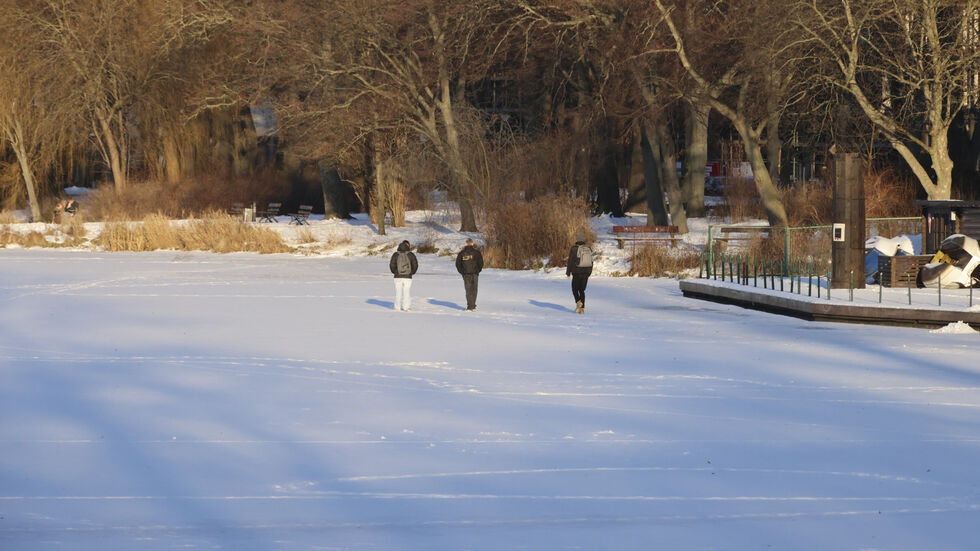 Menschen spazieren über den zugefrorenen Schlossteich