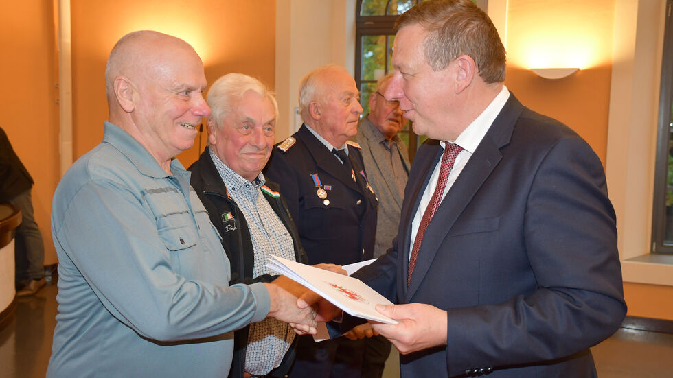 Landrat Christian Jaschinski (r.) gratuliert Löschmeister Franz Helmut Pohl aus Rückersdorf (Amt Elsterland) zur Medaille für 60 Jahre treue Dienste.