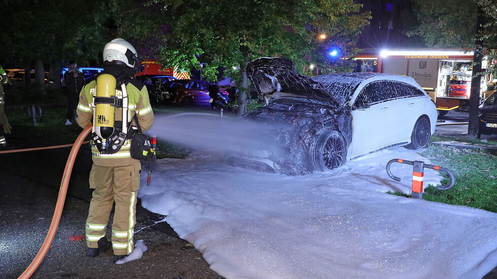 Die Feuerwehrleute löschten mit Wasser und Schaum die Feuerwehrleute das vor einem Wohnhaus abgestellte Fahrzeug