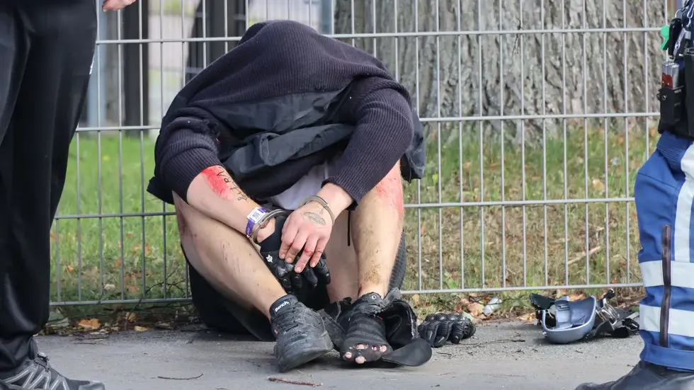 Mit Handschellen sitzt der Mann am Straßenrand. Die Knie sind aufgeschürft, ein Schuh ist zerfetzt. Neben ihm liegen Motorradkleidung und Ausrüstung. Mit Handschellen sitzt der Mann am Straßenrand. Die Knie sind aufgeschürft, ein Schuh ist zerfetzt. Neben ihm liegen Motorradkleidung und Ausrüstung.