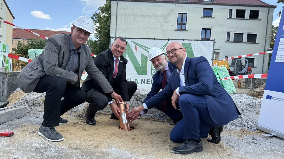 Von links: Schulleiter Christoph Koban, Landrat Udo Witschas, Thomas Graupner vom Kultusministerium und Bürgermeister Alexander Pötschke mit der Zeitkapsel. Die enthält u.a. Amtsblatt, Münzgeld, Projektplan und Förderbescheid. 